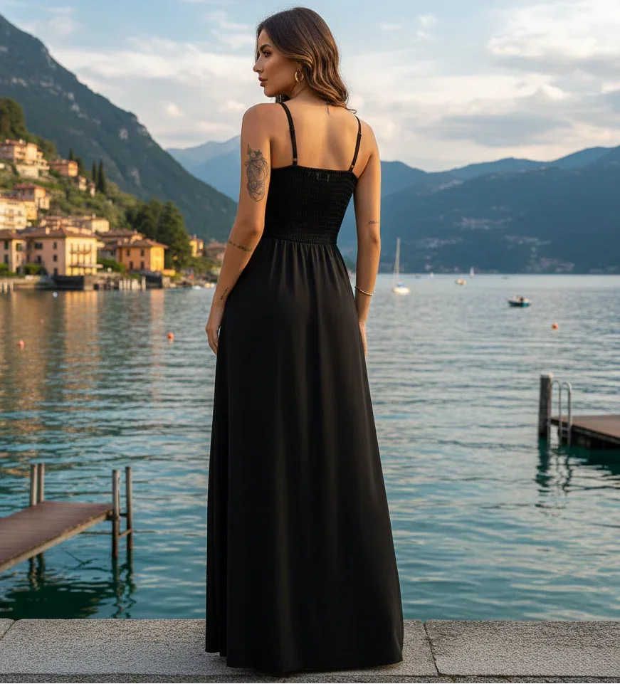 Mulher de costas vestindo vestido preto longo, à beira de um lago, cenário com montanhas.