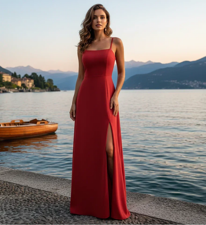 Mulher vestindo vestido longo vermelho com fenda, ao lado de lago ao entardecer